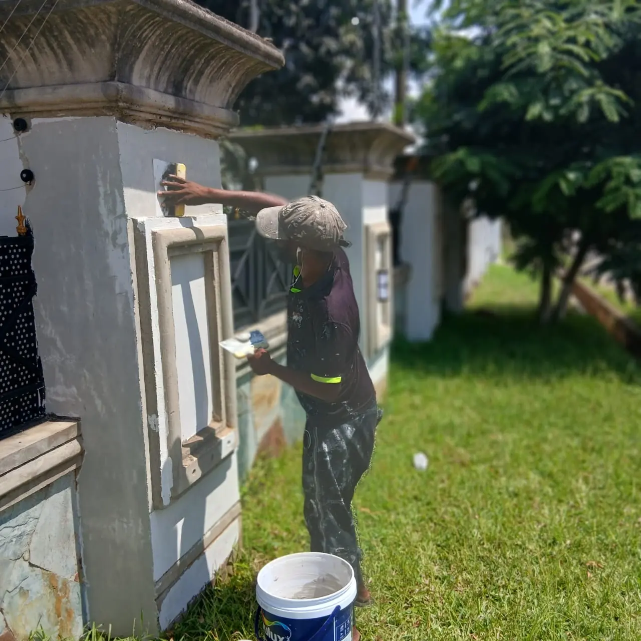 Worker painting external wall and gate area